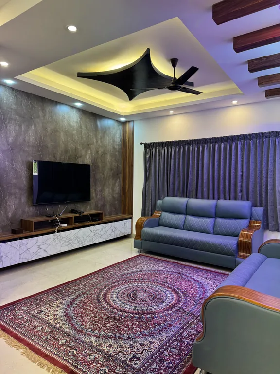 Living room with sofas, TV and a patterned rug in the Three Bedroom Apartment with Balcony at Marvee Luxus Stays, Ram Nagar, Coimbatore