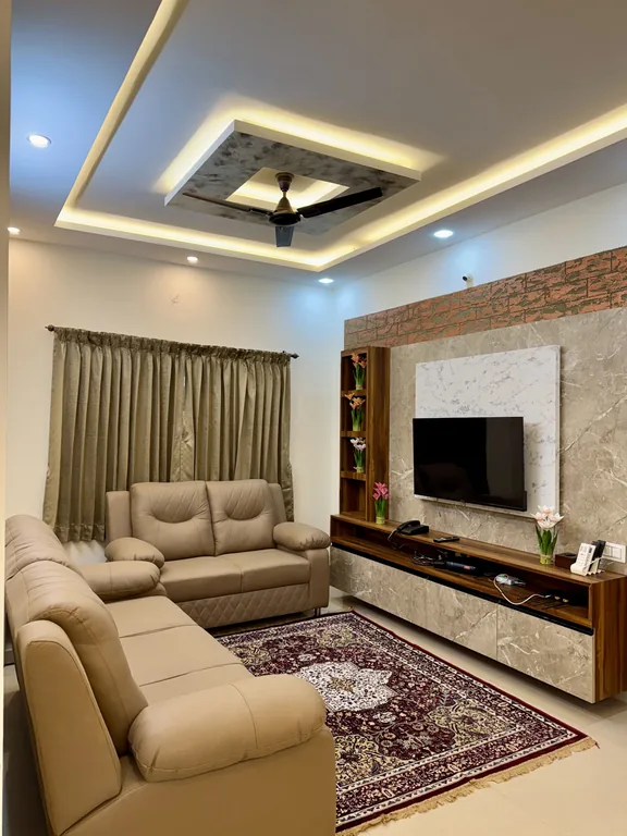 Living room with sofa seating and a wall mounted TV in the Two Bedroom Apartment with Balcony at Marvee Luxus Stays, Ram Nagar, Coimbatore